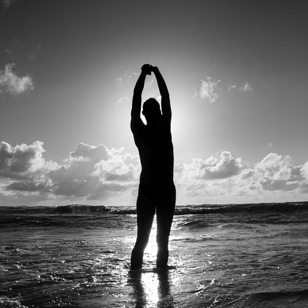 Silhouette of a man stretching against a sunrise, symbolizing energy.